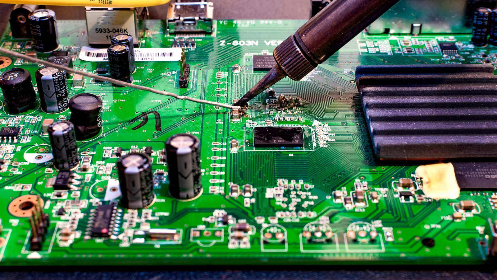 Technician soldering a replacement component onto a television power supply board