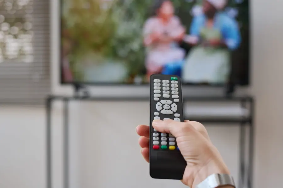 Person pressing buttons on a television remote control that is not responding